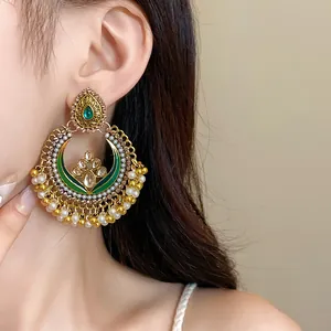 Detailed view of ethnic vintage gold drop earrings with pearls and green accents.
