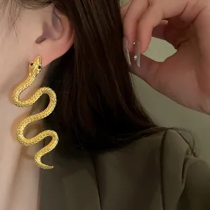 Gros plan de boucles d'oreilles dorées en forme de serpent avec texture d'écailles détaillée