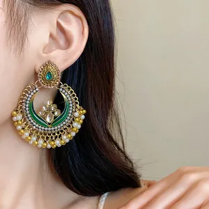 Detailed close-up of vintage ethnic gold chandelier earring with green enamel and pearls