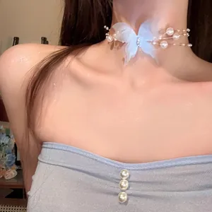 Close-up view of a delicate light blue fabric butterfly pearl choker on a model's neck