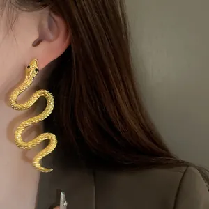 Gros plan d'un mannequin portant une boucle d'oreille dorée en forme de serpent avec écailles