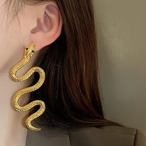 Gros plan d'une boucle d'oreille dorée en forme de serpent avec textures fines.