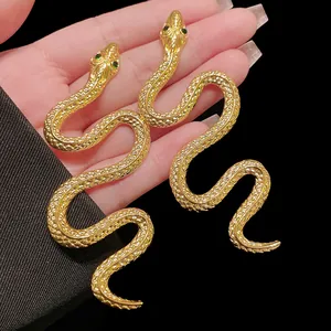 Vue détaillée de boucles d'oreilles en forme de serpent doré avec yeux en strass