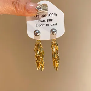 Detailed view of gold leaf fringe earrings with grey faux pearls on display card
