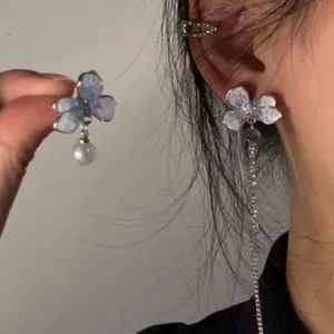 Dettaglio di orecchini floreali asimmetrici con perla e lunga nappa in azzurro chiaro