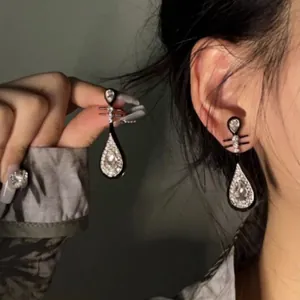Dettaglio delle eleganti orecchini a goccia neri con cristalli indossati da una modella asiatica