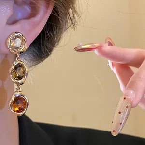 Close-up detail of vintage 18k gold plated drop earrings featuring oval amber stones