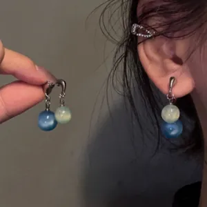 Eleganti orecchini pendenti in stile cinese con perle blu e bianche indossati all'orecchio
