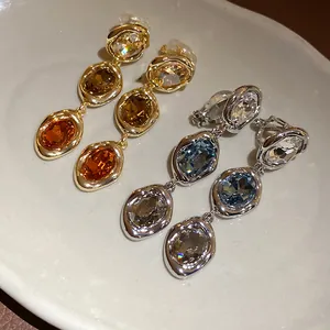 Detail view of vintage style triple oval crystal drop earrings in gold and silver