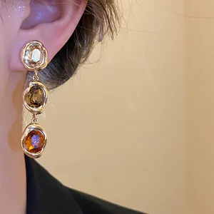 Detail shot of vintage 18k gold plated earrings featuring three stacked oval gemstones.