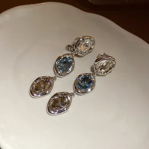 Vintage silver-plated drop earrings with blue and clear crystals on a white plate