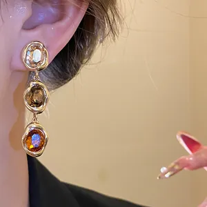 Macro view of vintage 18k gold-plated earrings with three-tiered amber oval stones.
