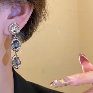Close-up of 18k gold plated vintage oval crystal drop earrings worn on a model's ear