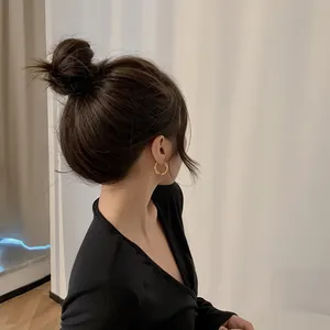Detailed view of minimalist gold twisted hoop earrings worn by an Asian model in a soft setting