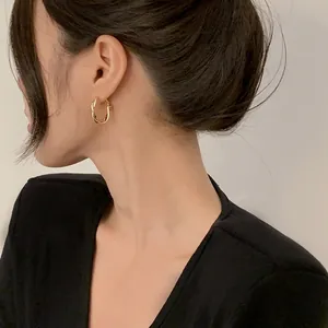 Close-up macro view of minimalist twisted gold hoop earrings on a model's ear