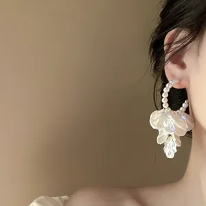 Detail view of elegant pearl hoop earring featuring delicate white flower petal tassels