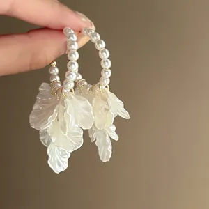 Close-up view of elegant pearl hoop earrings featuring delicate white petal tassel drops