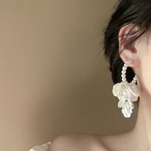 Elegant pearl hoop earrings with delicate white petal tassels on an Asian model