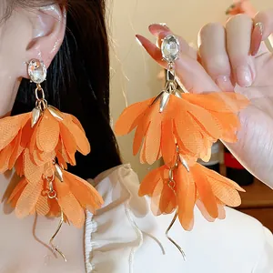 Dettaglio ravvicinato degli orecchini a fiore in chiffon arancione con strass lucidi