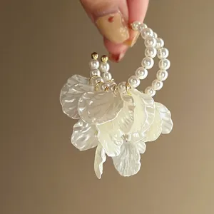 Detailed view of elegant pearl hoop earrings featuring layered white acrylic petal tassels
