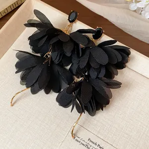 Dettaglio macro degli eleganti orecchini a fiore in chiffon nero con ganci dorati
