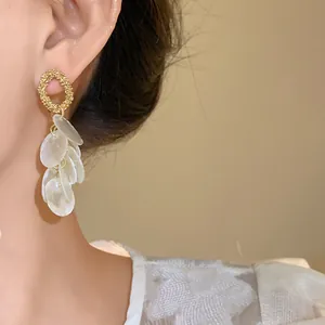 Primer plano detallado de elegantes pendientes de borla de concha blanca y oro en oreja
