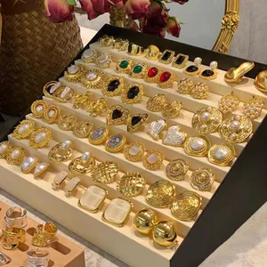 Close-up display of multiple vintage French style gold-plated earrings on stand