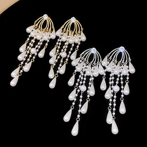 Primer plano de elegantes pendientes de borla en oro y plata con perlas de gota de agua.