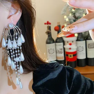 Elegantes pendientes de borla con perlas y circonitas en la oreja de una modelo