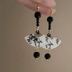 Close-up detail of elegant Chinese style fan earrings with bamboo pattern and black beads