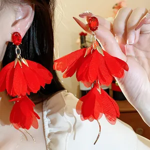Primo piano di eleganti orecchini a fiore in chiffon rosso con perni in pietra preziosa