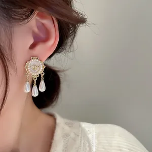 Detailed close-up of vintage French style gold-tone earrings with elegant teardrop pearls.