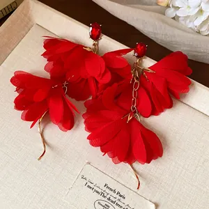 Primo piano di eleganti orecchini a fiore in chiffon rosso con pietre preziose rosse