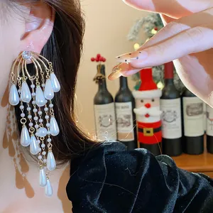 Vista detallada de elegantes pendientes dorados con perlas blancas en forma de gota y circonitas.