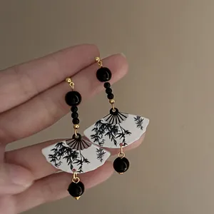 Detailed view of Chinese style resin fan earrings with bamboo pattern and black beads.