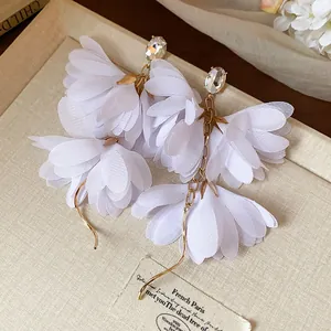 Eleganti orecchini a fiore in chiffon bianco con strass trasparenti in vista ravvicinata