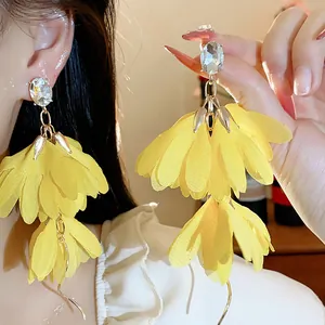 Vista dettagliata di orecchini a fiore in chiffon giallo con un cristallo chiaro brillante