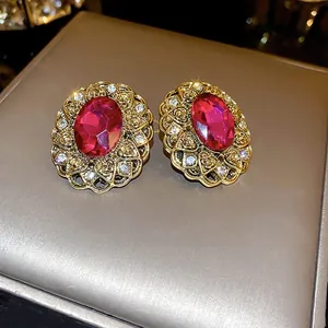 Close-up of vintage French style earrings with red main stone and gold floral border