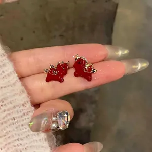 Detailed close-up view of red cartoon winged horse stud earrings with golden wings