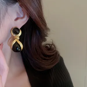 Close-up of vintage French style teardrop earrings with black resin and gold finish