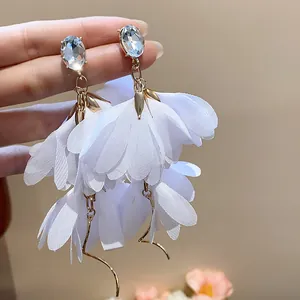 Primo piano di orecchini a fiore in chiffon bianco con eleganti borchie in strass ovali.