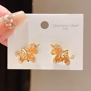 Close-up of gold-plated unicorn stud earrings with orange inlay on 316L steel card.
