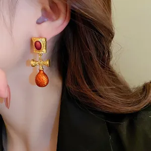 Detail view of French vintage drop earrings with textured gold and orange enamel