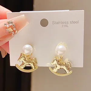 Detailed view of rocking horse pearl earrings on a 316L stainless steel display card