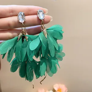 Dettaglio di orecchini a fiore in chiffon verde smeraldo con perni di cristallo ovali