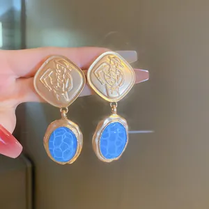 Close-up detail of French vintage gold-tone earrings with textured blue oval drops.