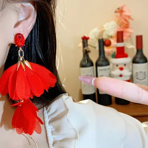 Primo piano di orecchini a fiore in chiffon rosso con cristallo sull'orecchio del modello