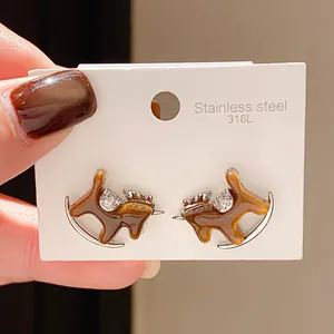Detailed view of amber-colored rocking horse stud earrings on a white stainless steel card.