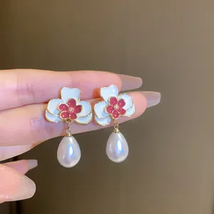 Close-up of vintage flower earrings with white enamel petals and pearl drops