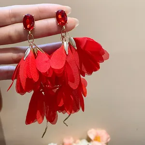 Primo piano di eleganti orecchini a fiore in chiffon rosso con perni in cristallo rubino
